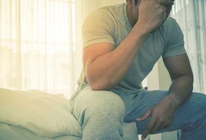 sad man on edge of bed